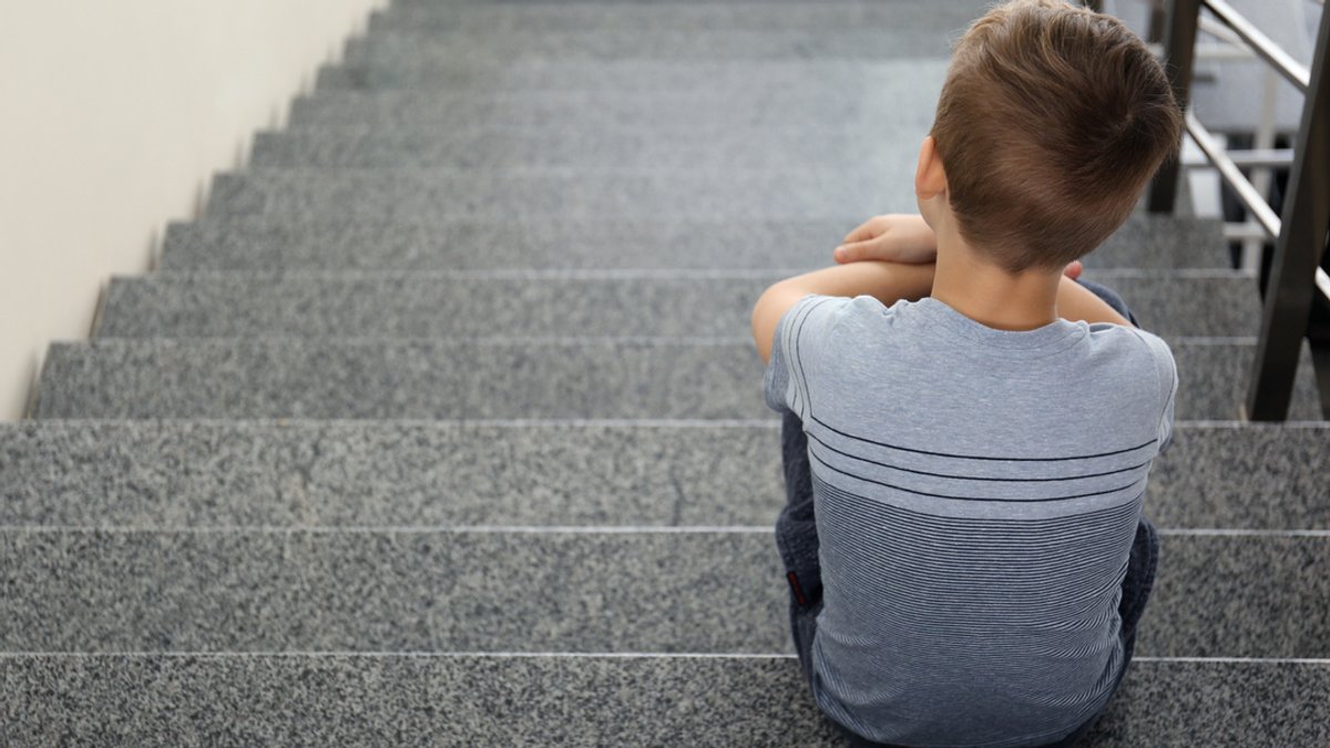 Ein Kind sitzt auf einer Treppe. Symbolbild.