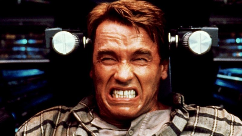 Arnold Schwarzenegger sitzt mit verzerrtem Blick in einem Sitz (Filmstill aus "Total Recall", 1990)
