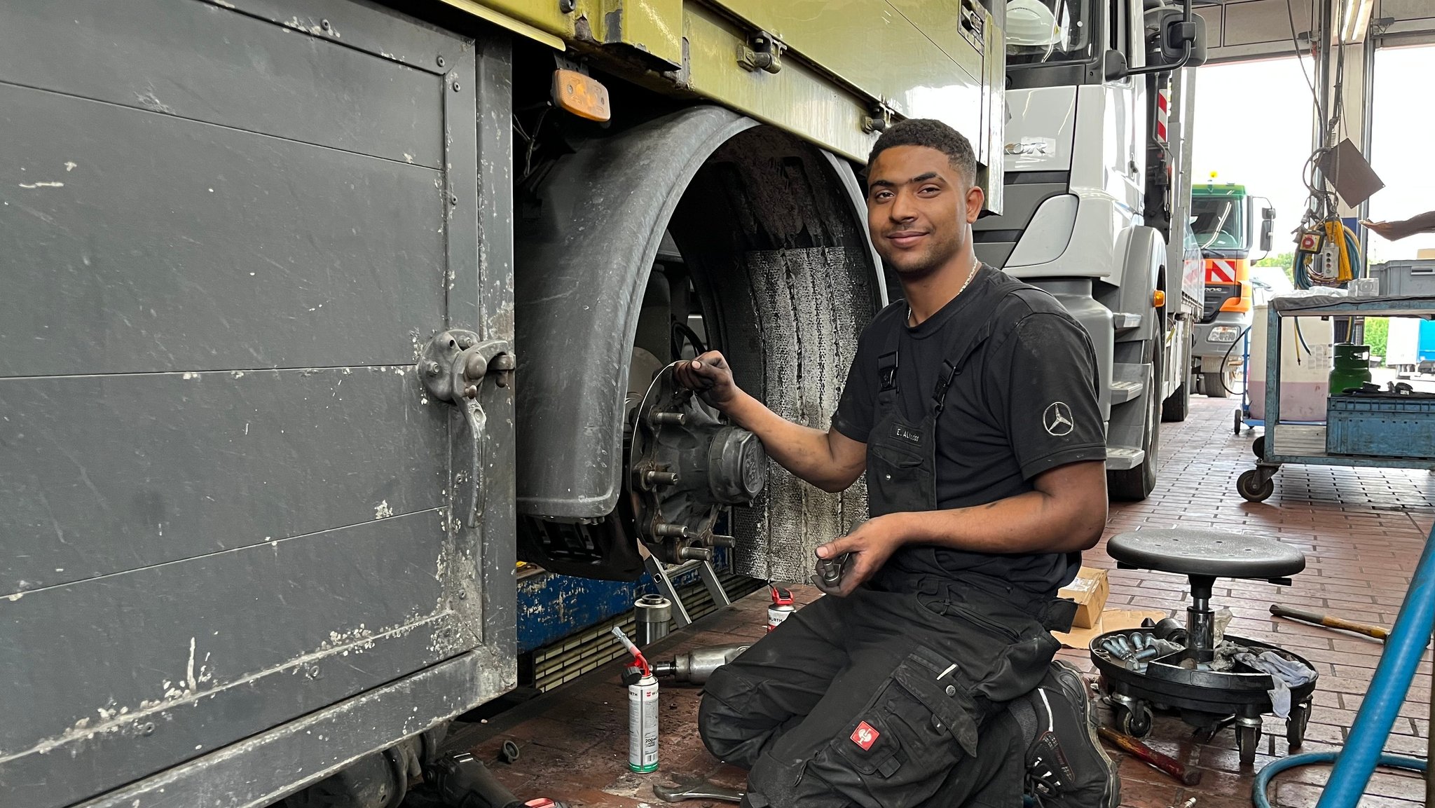 Esam A. kniet in der Werkstatt an einem Lkw.