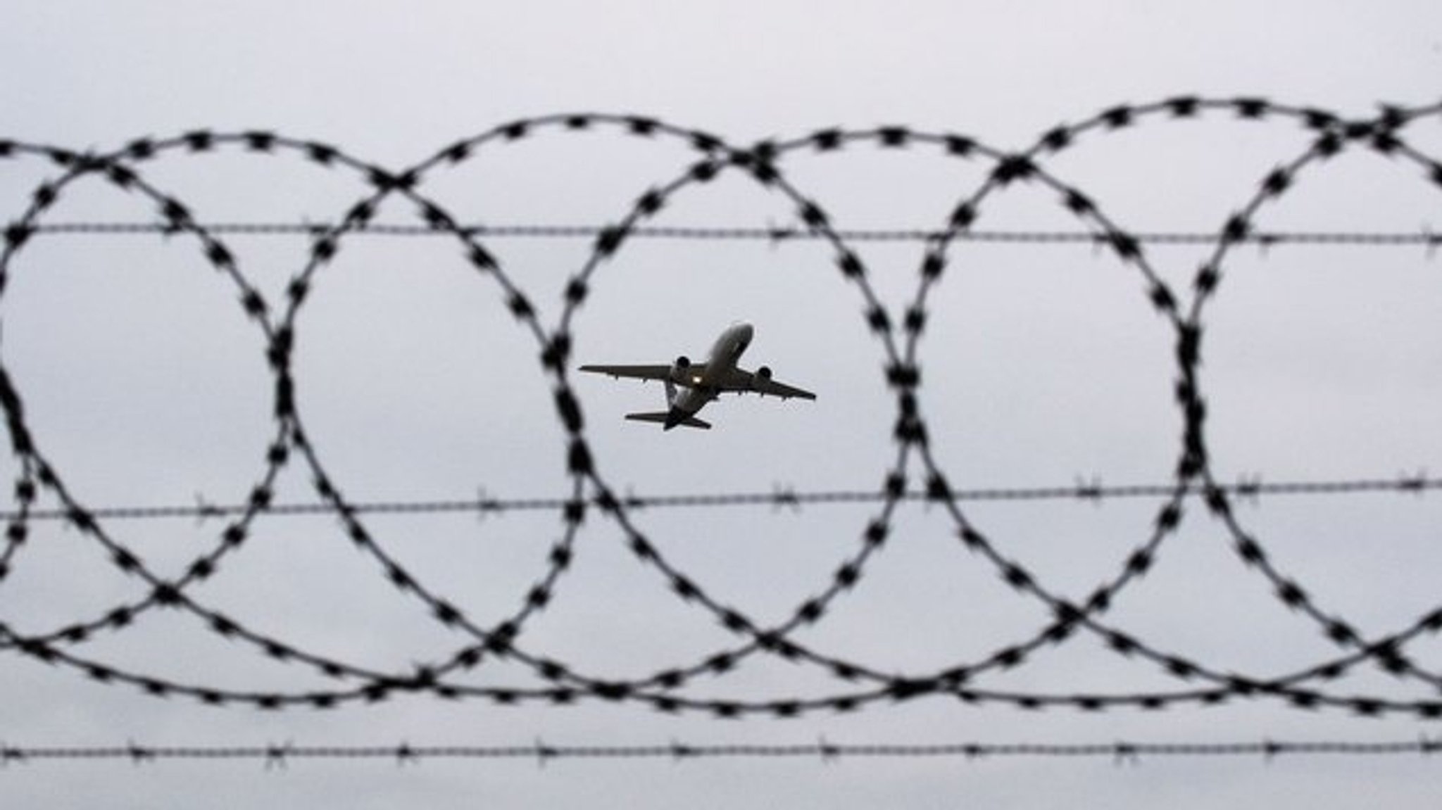 Symbolbild: Flugzeug hinter Stacheldraht