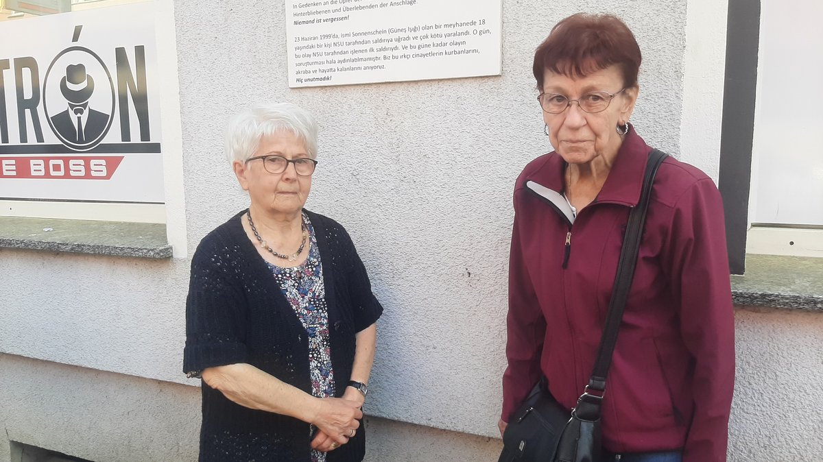 Zwei Anwohnerinnen stehen in der Scheurlstraße vor einer Tafel, die an den NSU-Anschlag erinnert 
