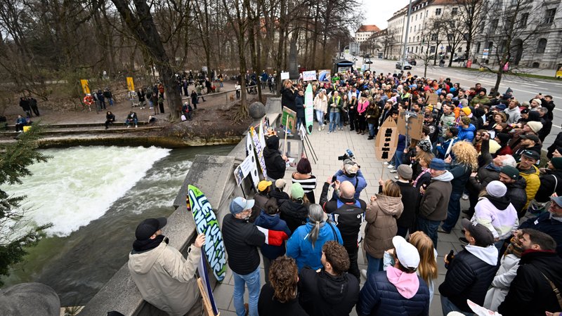 An der Eisbachwelle stehen zahlreiche Protestierende, teilweise mit Pappschildern | Bild: picture alliance/dpa | Felix Hörhager An der Eisbachwelle stehen zahlreiche Protestierende, teilweise mit Pappschildern