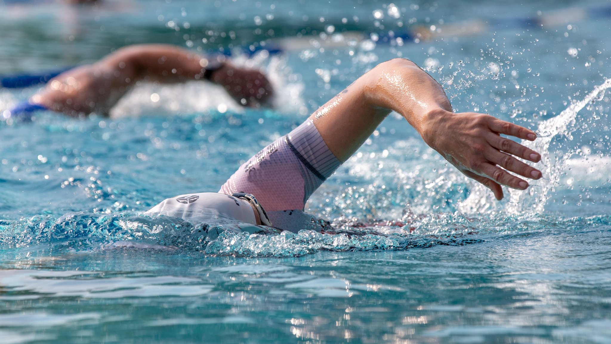 Zwei Männer kraulen im Wasser.