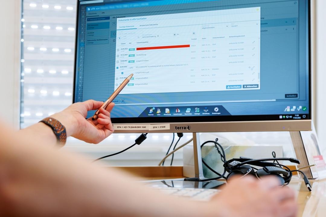 Ein Hausarzt lädt in seiner Praxis Dokumente in eine elektronische Patientenakte ePA. 