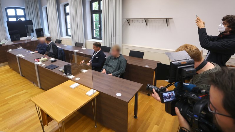Ein Landwirt (l) und sein Sohn (r) sitzen mit ihren Anwälten im Landgericht auf der Anklagebank. 