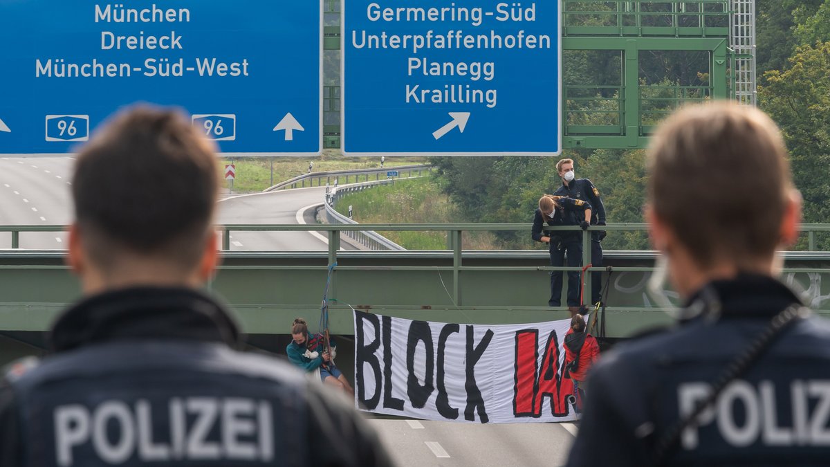 Aktivisten nehmen an einer Banneraktion an einer Brücke über der Autobahn A96 bei Germering teil.