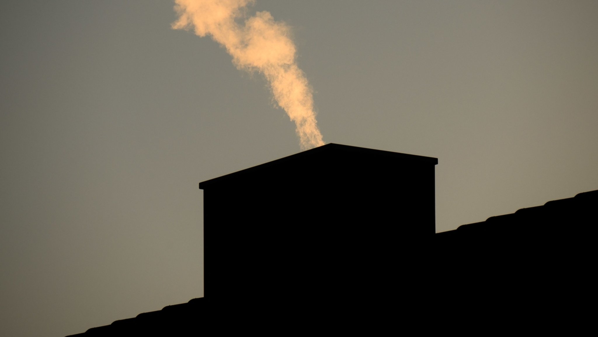 Aus dem Kamin eines Hauses steigt Rauch auf.