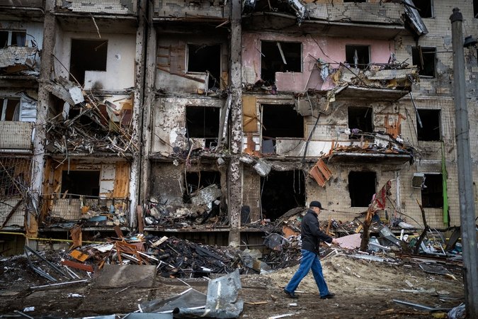 25.02.2022, Ukraine, Kiew: Ein Mann geht an einem Gebäude vorbei, das nach einem Raketenangriff beschädigt wurde. Russische Truppen haben am Donnerstag, 24.02.2022, den erwarteten Angriff auf die Ukraine gestartet.