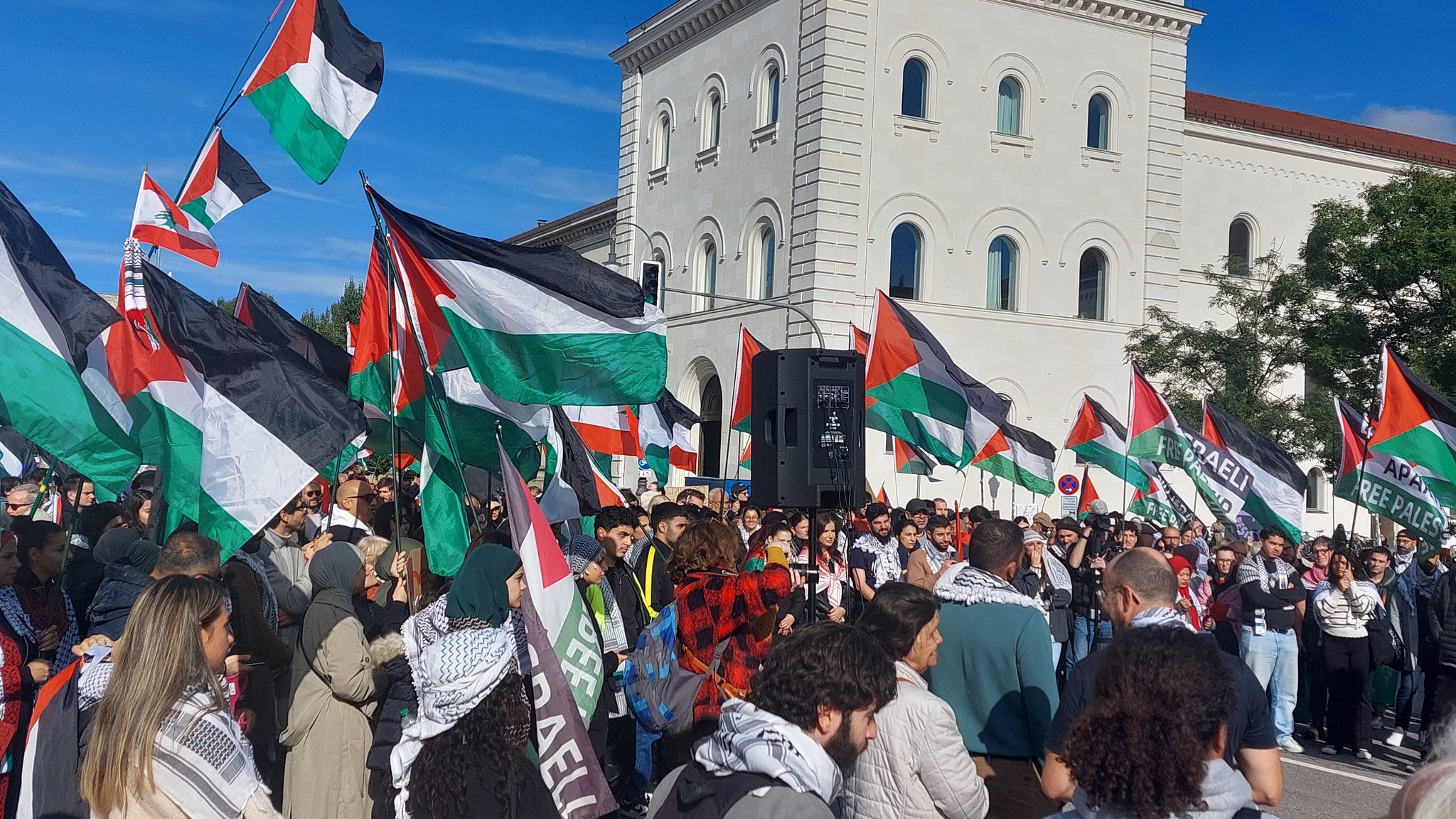 Teilnehmer einer pro-palästinensischen Kundgebung am Geschwister-Scholl-Platz mit Palästina-Flaggen..