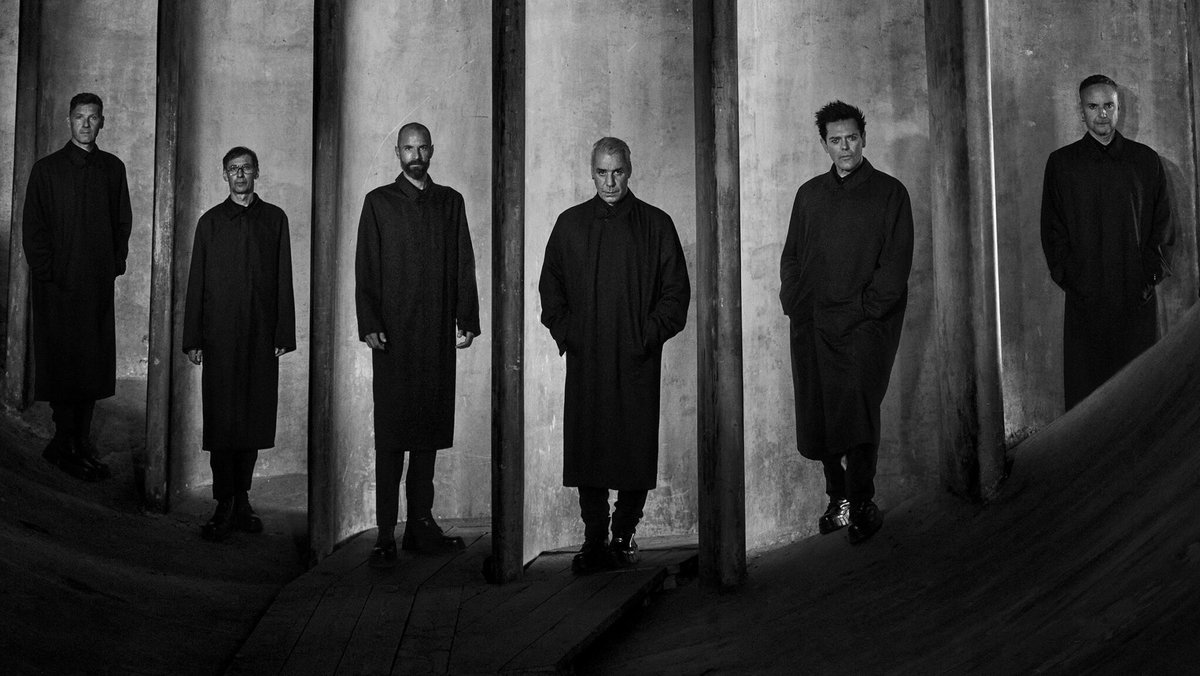 Schwarzweißfotografie von sechs Männern in dunklen Mänteln