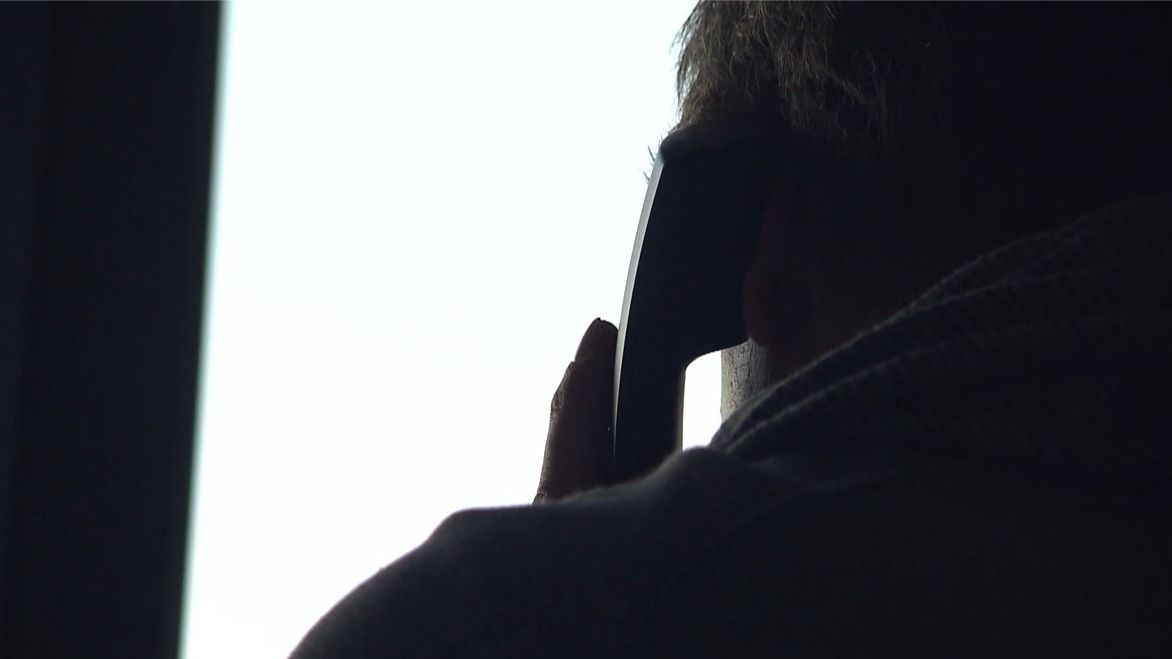 Eine ältere Person hält einen Telefonhörer ans Ohr.