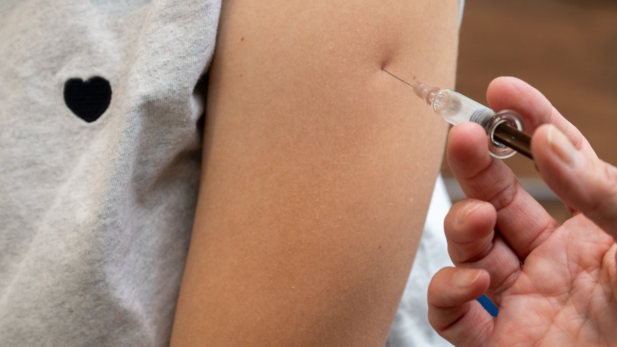 Ärztin setzt zur HPV-Impfung eine Injektion in den Oberarm einer Jugendlichen.