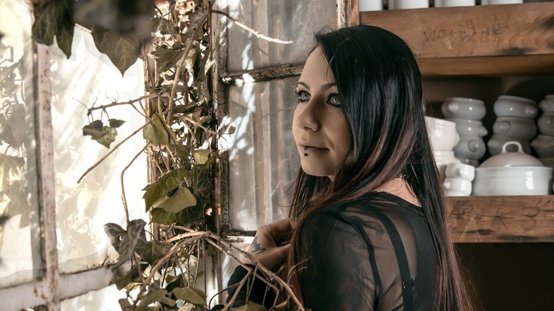 Eine Frau in schwarzer Kleidung steht in einem alten Porzellanlager. | Bild: Reinhard Frank Eine Frau in schwarzer Kleidung steht in einem alten Porzellanlager.