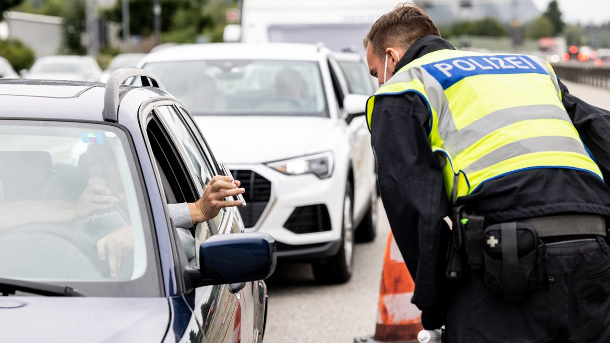 Autofahrer zeigt einem Bundespolizisten an der Grenze zu Österreich auf der Autobahn A93 digitalen Impfnachweis auf dem Smartphone.