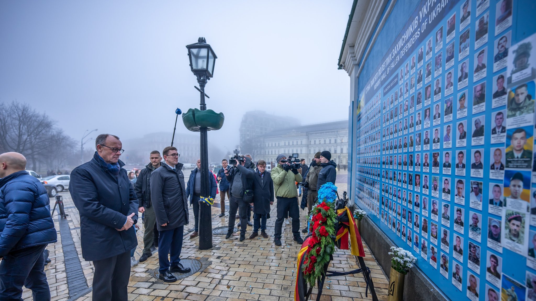 Friedrich Merz (l), Unions-Kanzlerkandidat und CDU-Bundesvorsitzender, steht an der Mauer des Gedenkens an die im Krieg gefallenen Soldatinnen und Soldaten auf dem Michaelsplatz.