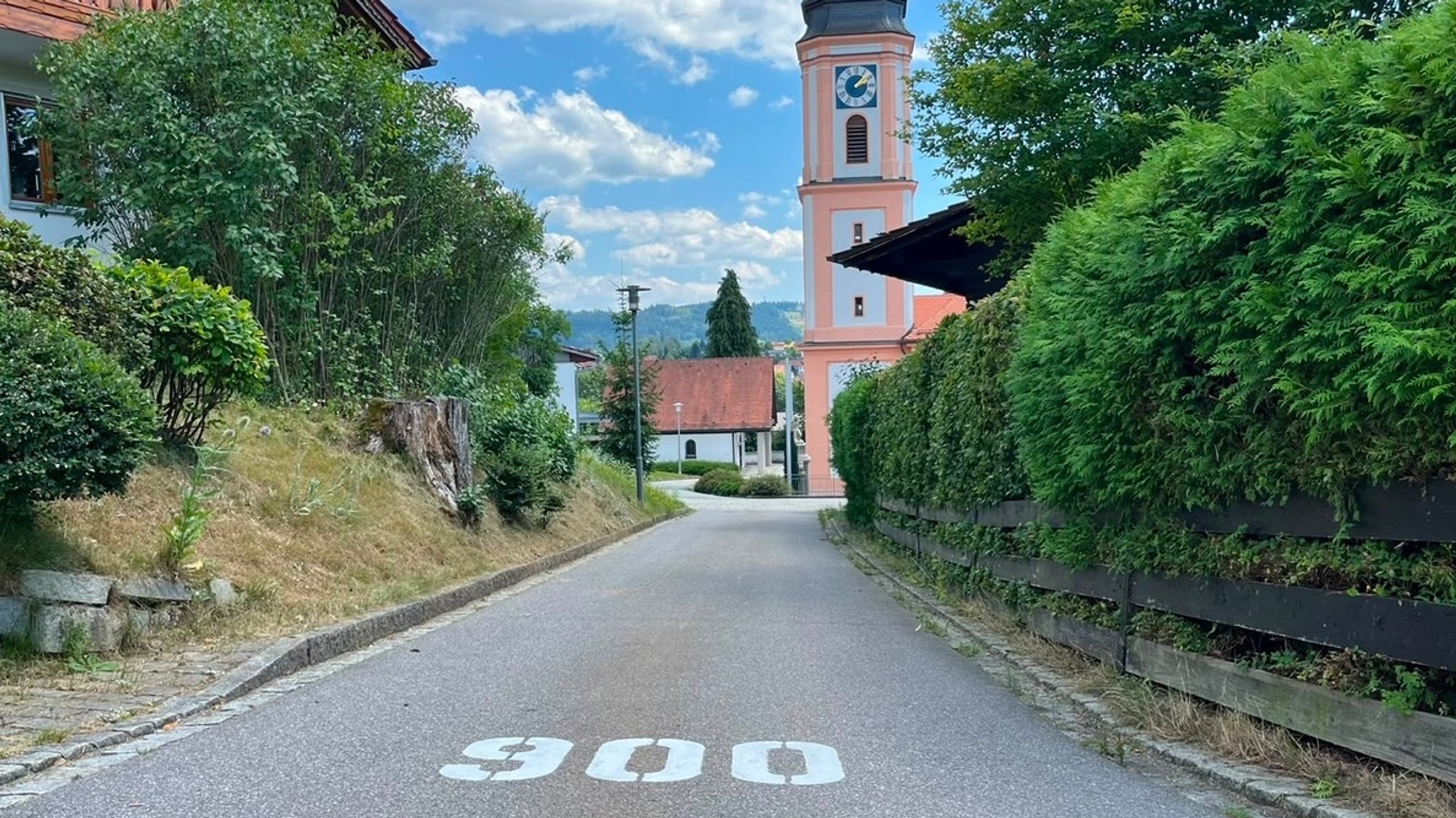 Eine Bodenmarkierung mit der Zahl 900, dahinter zu sehen sind Häuser und eine Kirche. | Bild: Axel T Schmidt Eine Bodenmarkierung mit der Zahl 900, dahinter zu sehen sind Häuser und eine Kirche.