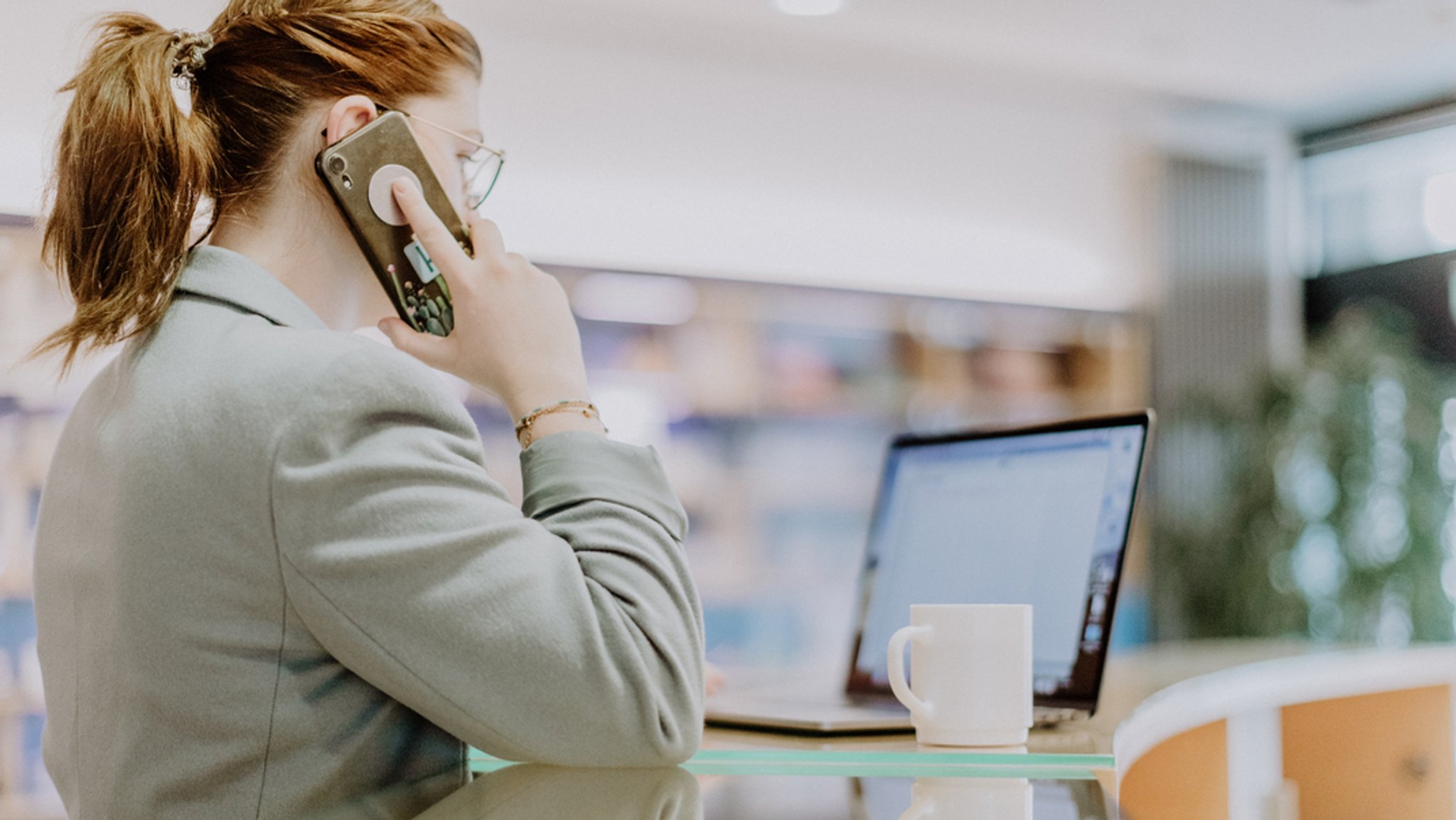 Eine Frau arbeitet am Laptop und telefoniert.