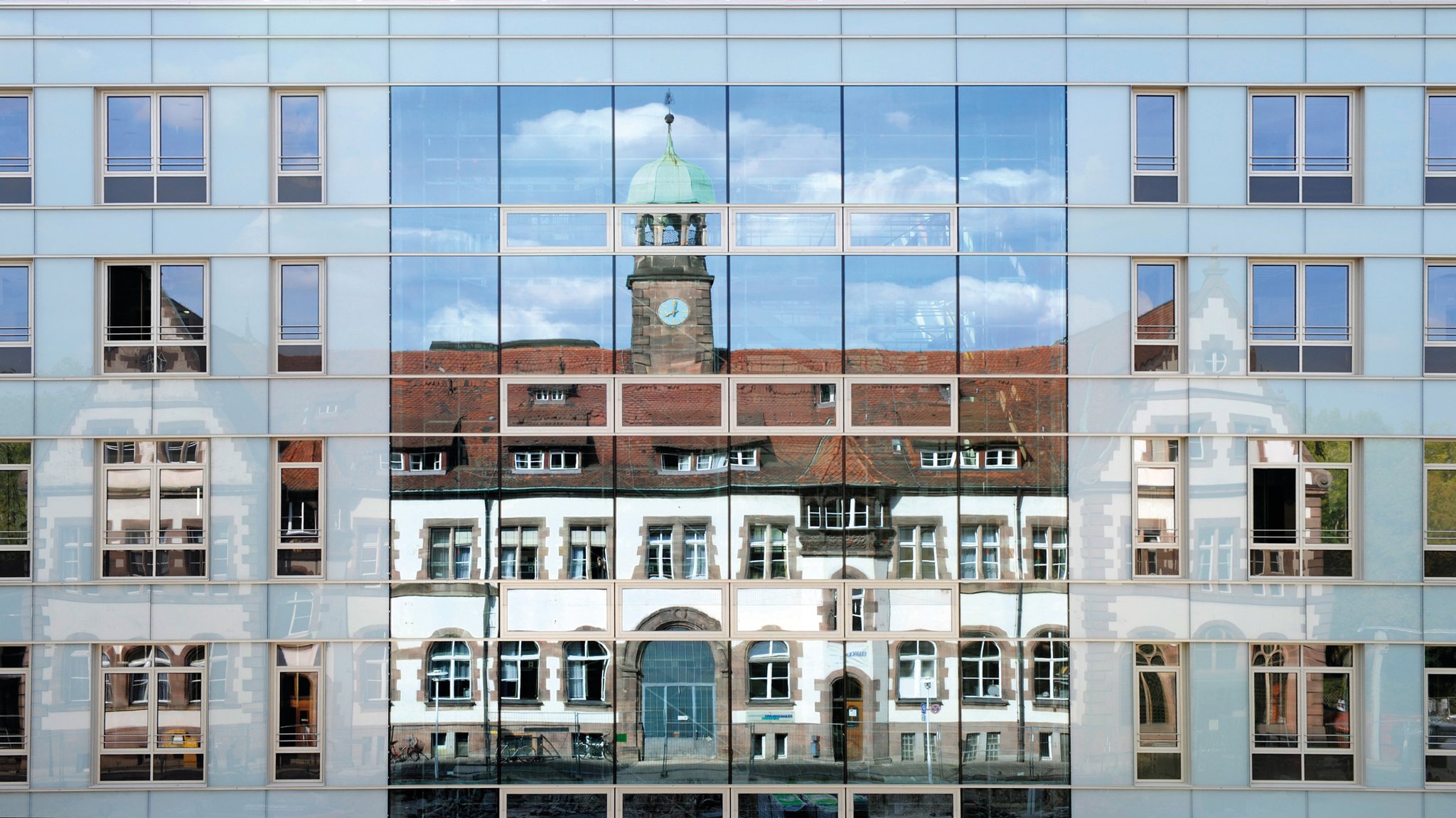 Ein Haus des Klinikums Nürnberg-Nord spiegelt sich in einer Fensterfassade.