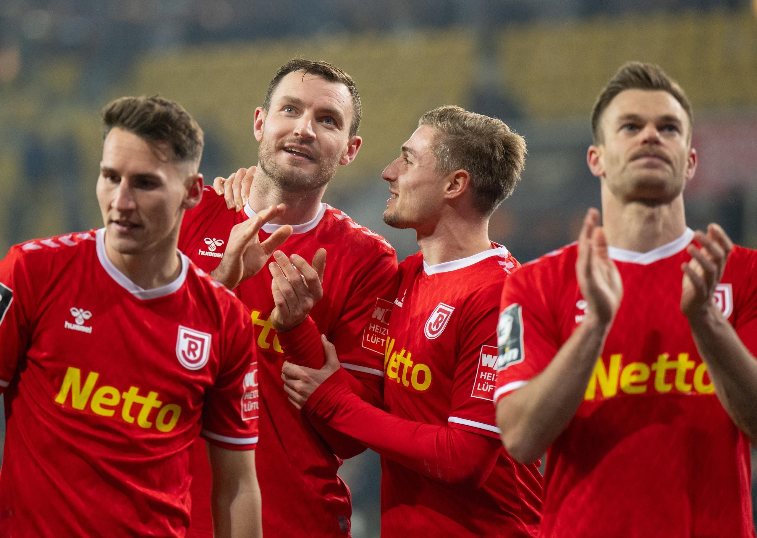 ARCHIV - 26.11.2023, Sachsen, Dresden: Fußball: 3. Liga, SG Dynamo Dresden - SSV Jahn Regensburg, 16. Spieltag, Rudolf-Harbig-Stadion. Regensburgs Konrad Faber (l-r), Florian Ballas, Elias Huth und Benedikt Saller jubeln nach dem Sieg. Dem Verein ist der Umbruch nach dem Abstieg gelungen. 