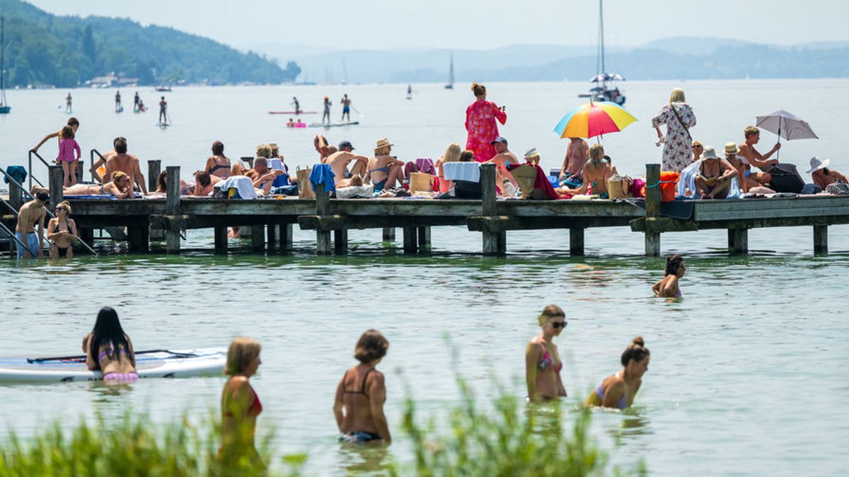 18.06.2023, Bayern, Percha: Sonnenhungrige genießen am Vormittag das warme Wetter auf einem Steg am Starnberger See. Foto: Peter Kneffel/dpa +++ dpa-Bildfunk +++
