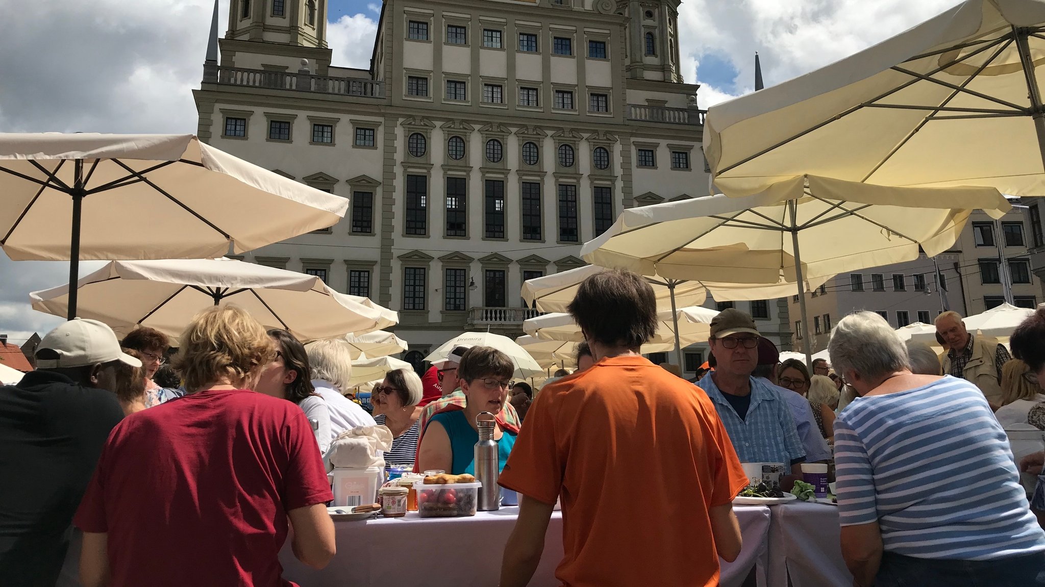 Die Friedenstafel auf dem Rathausplatz Augsburg im Jahr 2019: Viele Menschen sitzen an langen Tischen und essen gemeinsam