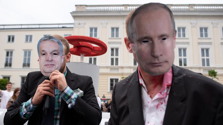 Demonstranten in Warschau protestieren - maskiertals Russlands Präsident Wladimir Putin und Ungarns Premierminister Viktor Orban - vor einer Attrappe einer Gaspipeline. | Bild:picture alliance / ZUMAPRESS.com | Aleksander Kalka
