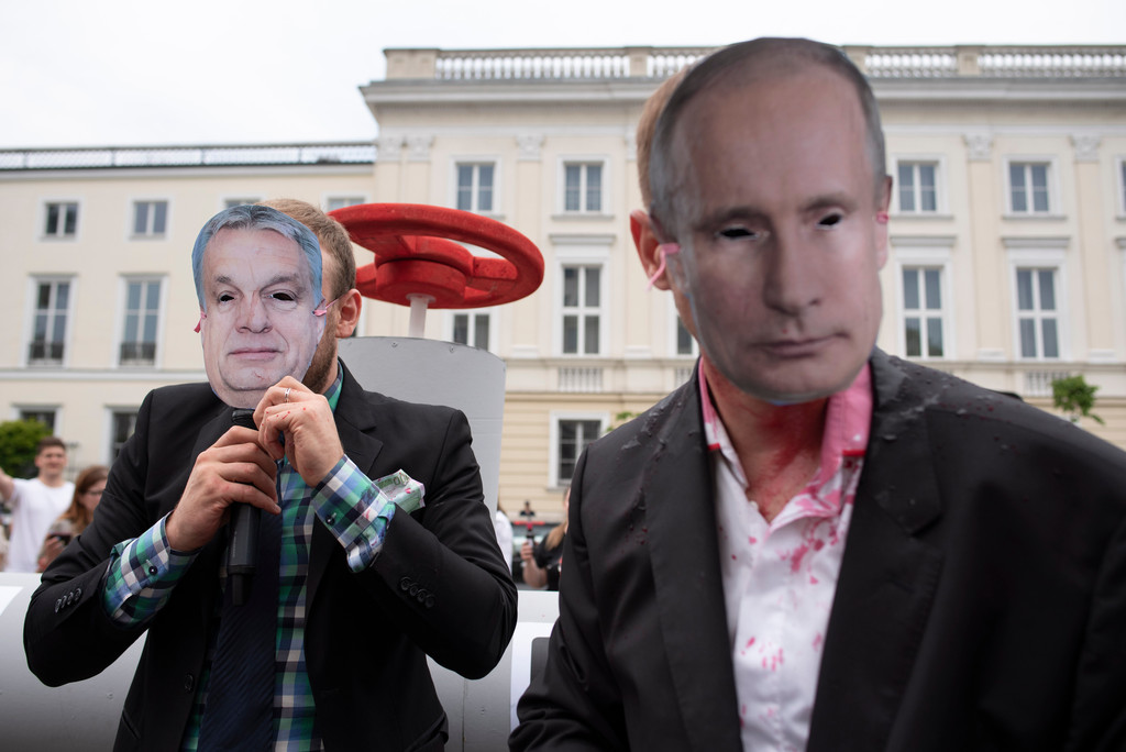 Demonstranten in Warschau protestieren - maskiertals Russlands Präsident Wladimir Putin und Ungarns Premierminister Viktor Orban - vor einer Attrappe einer Gaspipeline.