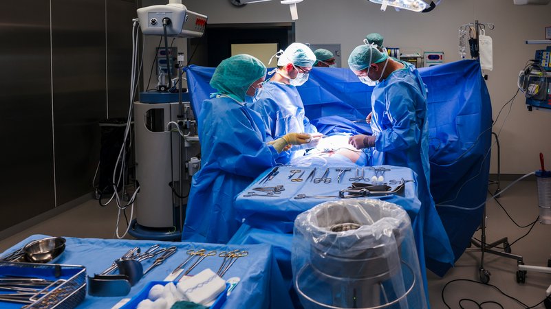 Ärzte und OP-Personal stehen während einer Operation am OP-Tisch