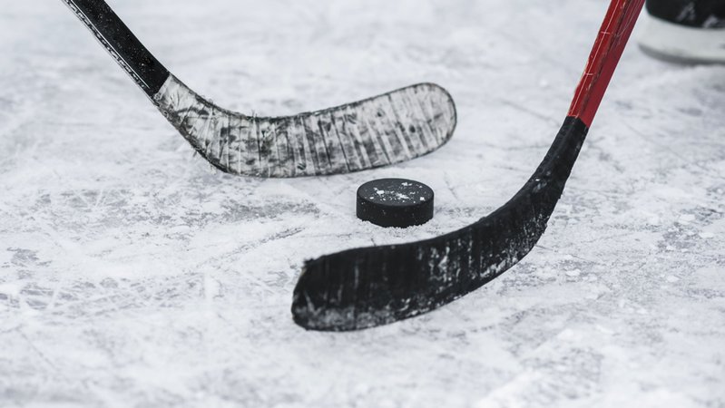 Zwei Eishockeyschläger und ein Puck. | Bild: stock.adobe.com/johnalexandr Zwei Eishockeyschläger und ein Puck.