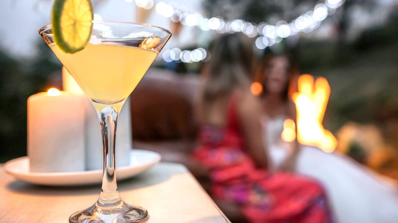 Ein Cocktailglas, im Hintergrund sitzen Frauen (Symbolbild) | Bild: picture alliance / Westend61 | David Pereiras Ein Cocktailglas, im Hintergrund sitzen Frauen (Symbolbild)