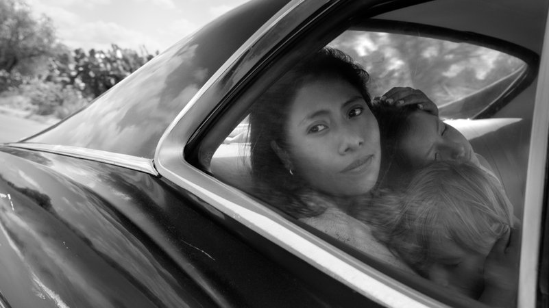 Filmszene aus "Roma": Kindermädchen Cleo sitzt im Auto, zwei Kinder auf dem Schoß, und blickt aus dem Fenster