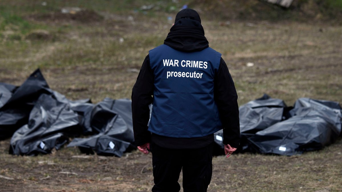 Ein Ermittler mit "War Crimes Prosecutor"-Weste ("Ankläger für Kriegsverbrechen") vor Leichen aus einem Massengrab in Butscha.