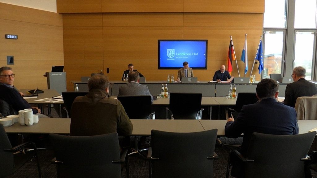 In einem Saal sitzen Männer und tagen. | Bild: BR In einem Saal sitzen Männer und tagen.