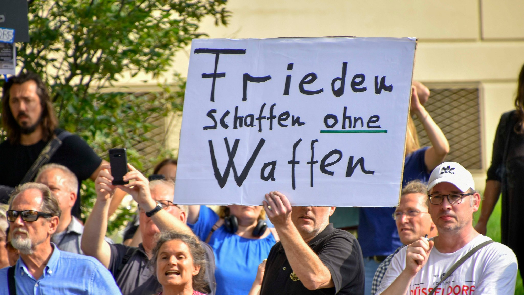 Ein Demonstrant hält ein Schild hoch: "Frieden schaffen ohne Waffen"