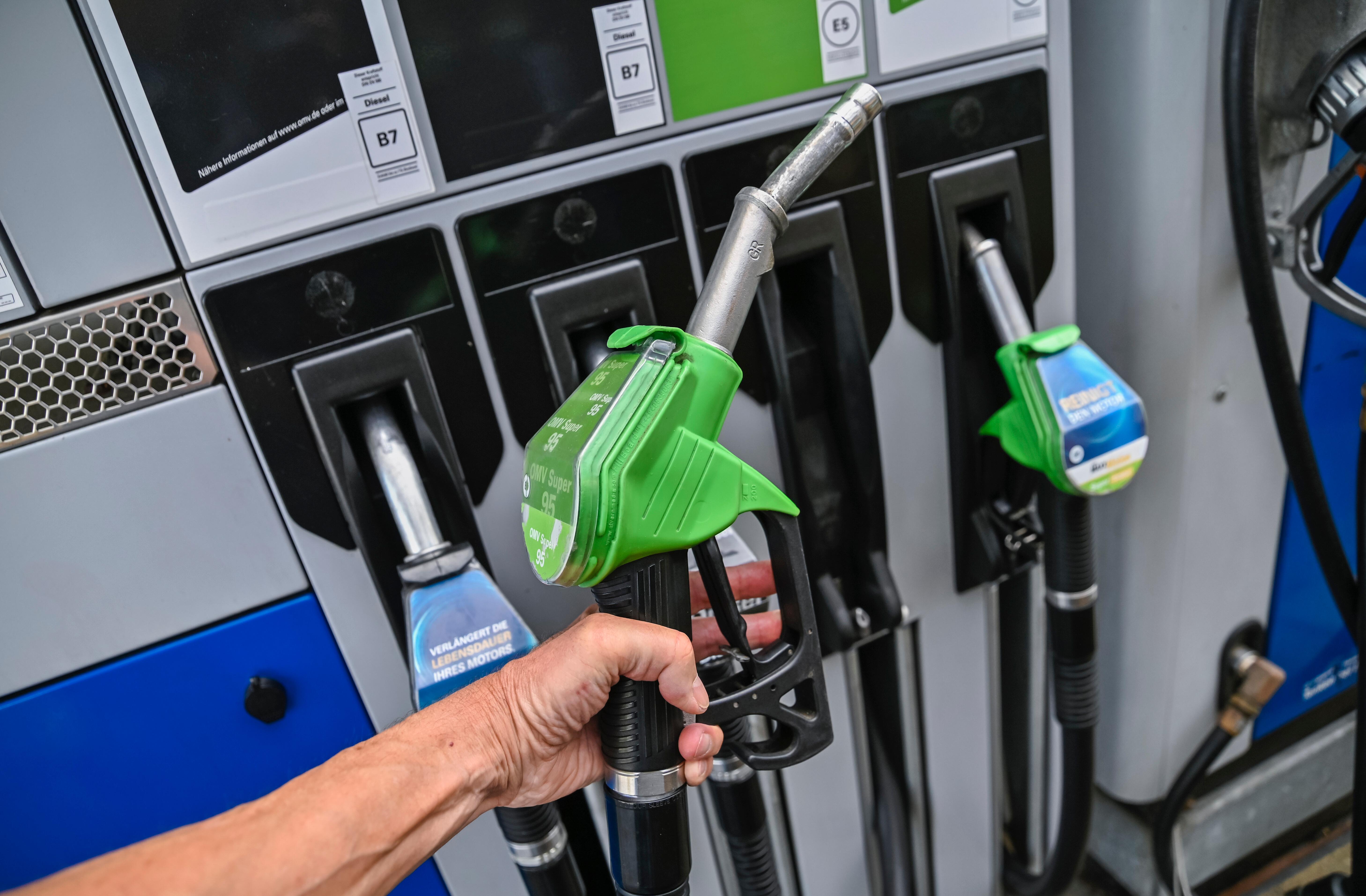 Eine Hand greift an einer Zapfsäule einen Zapfhahn.