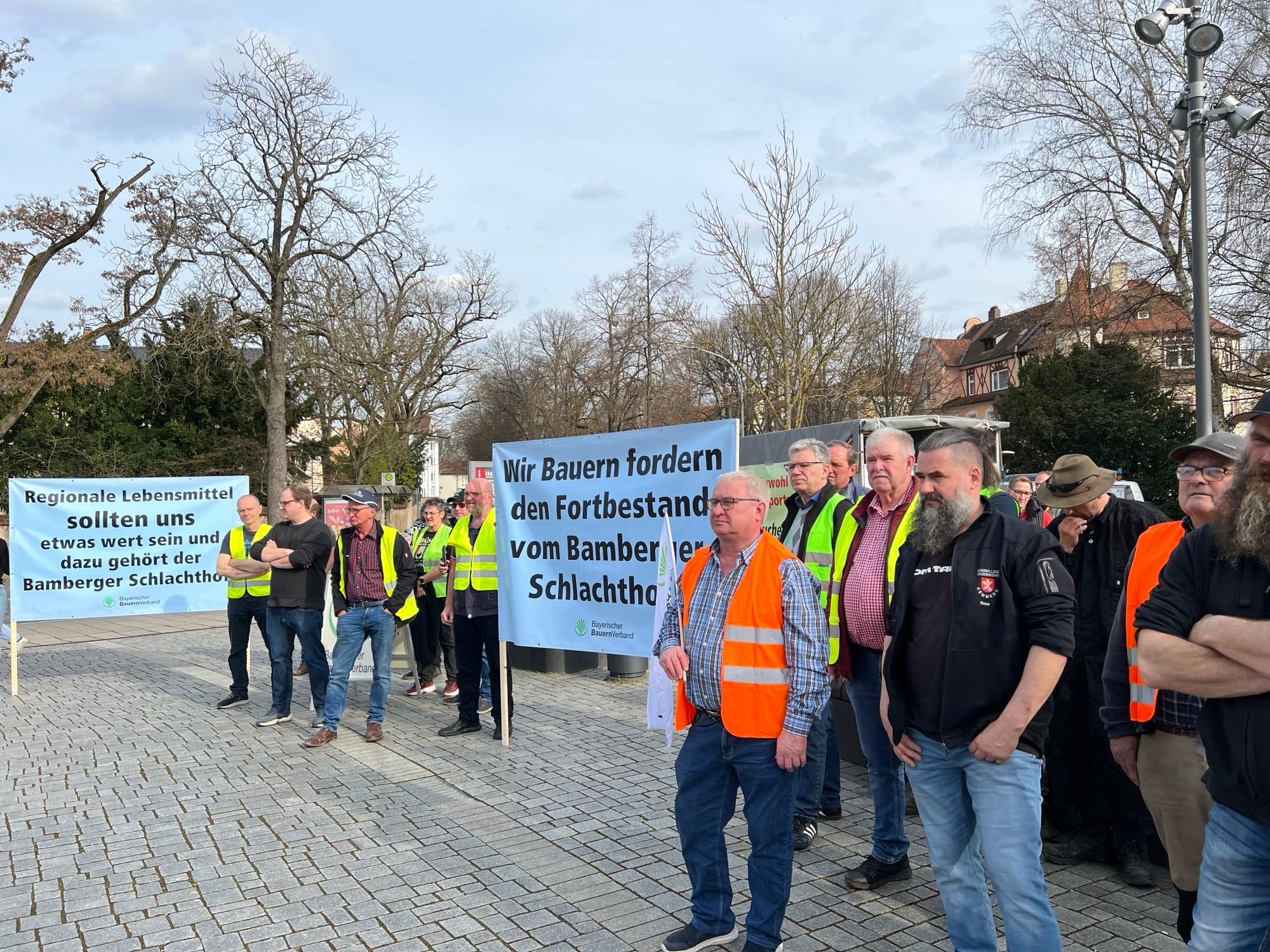Landwirte halten Transparente in den Händen, auf denen sie den Fortbestand des Bamberger Schlachthofs fordern. 