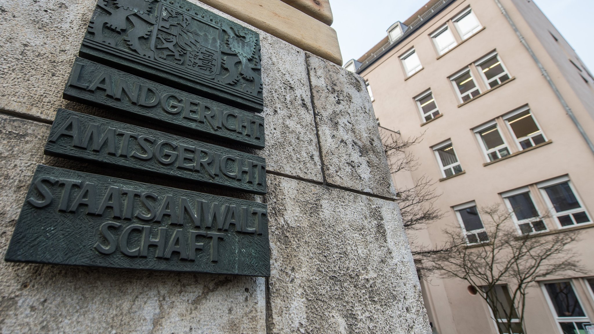 Ein Schild mit der Aufschrift "Landgericht, Amtsgericht, Staatsanwaltschaft" hängt in Regensburg an einer Außenwand eines Gerichtsgebäudes.