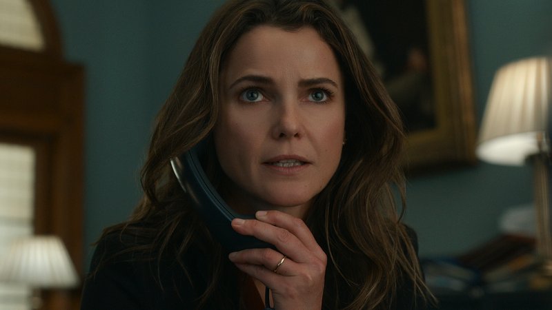Die Schauspielerin Keri Russell am Telefon. Sie schaut angestrengt geradeaus, sitzt vor verschwommenem Hintergrund. Eine Szene aus "Diplomatische Beziehungen" | Bild: 2023 Netflix, Inc. Die Schauspielerin Keri Russell am Telefon. Sie schaut angestrengt geradeaus, sitzt vor verschwommenem Hintergrund. Eine Szene aus "Diplomatische Beziehungen"