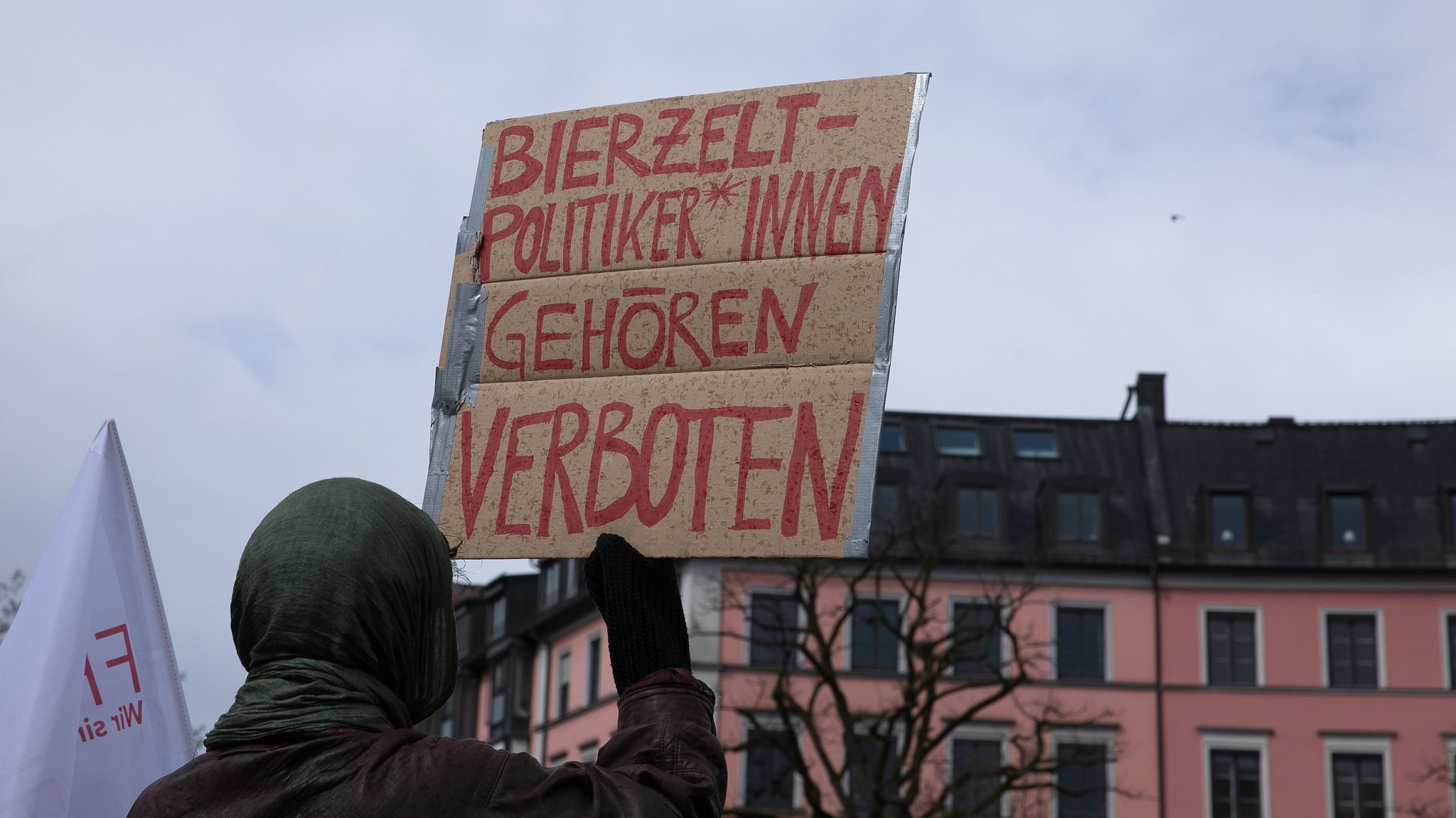 Ein Demonstrant hält ein Plakat bei einer Demonstration hoch, auf dem steht: Bierzeltpolitikerinnen gehören verboten. Vor dem "innen" ist ein Gender-Sternchen gesetzt