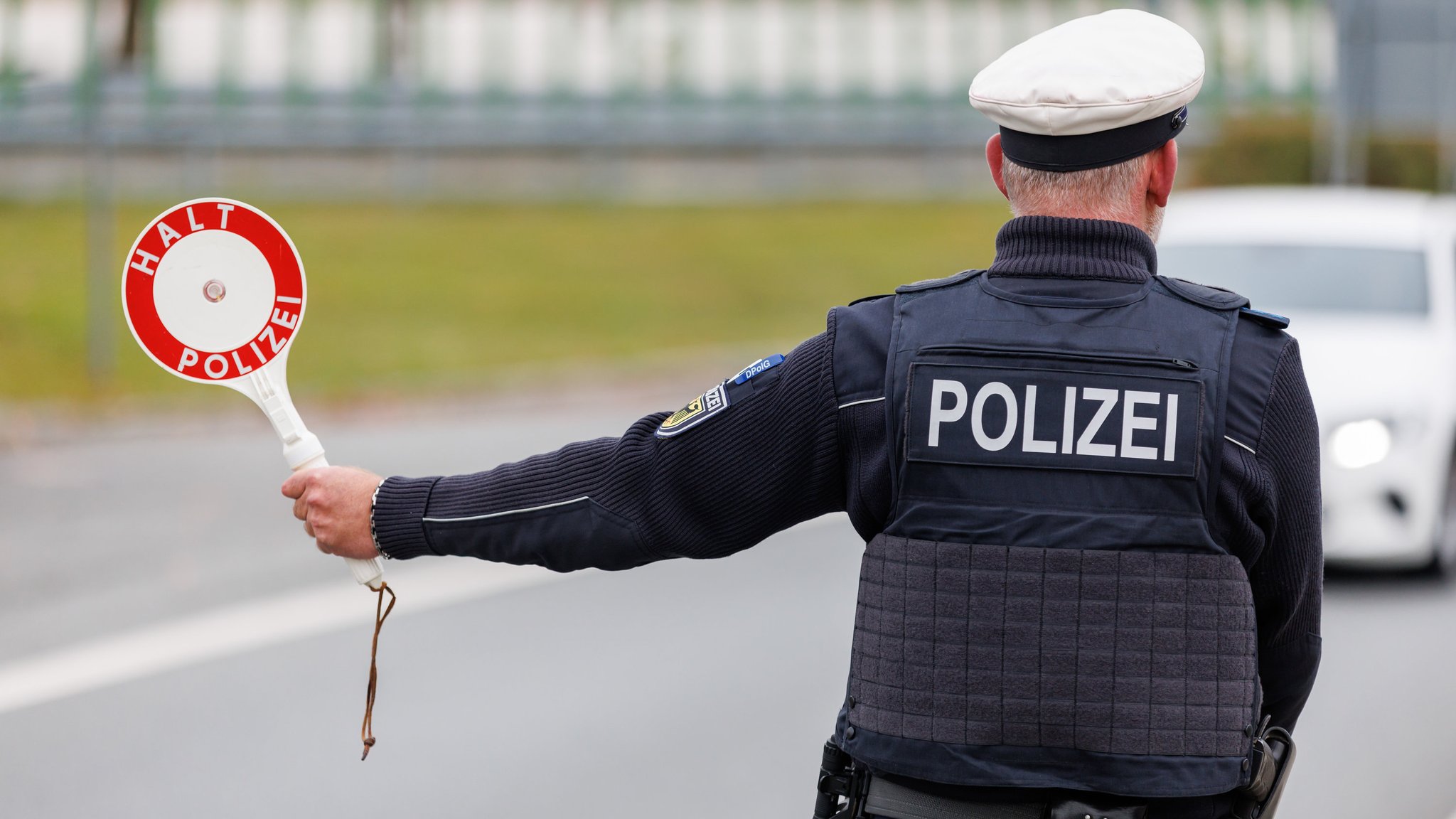 ARCHIV - 18.10.2023, Bayern, Furth im Wald: Ein Beamter der Bundespolizei stoppt bei der Kontrolle des Einreiseverkehrs am deutsch-tschechischen Grenzübergang Furth im Wald - Ceska Kubice den Fahrer eines Autos bei der Einreise. (zu dpa: «Schlag gegen mutmaßliche Schleuserbande - drei Festnahmen») Foto: Daniel Karmann/dpa +++ dpa-Bildfunk +++