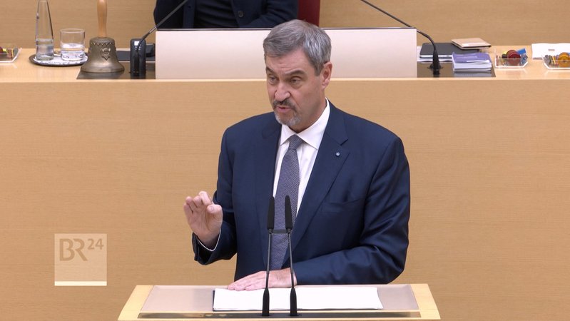 Der Bayerische Ministerpräsident versucht Optimismus zu verbreiten. Bei allen aktuellen Schwierigkeiten - Wirtschaftskrise, Ukraine-Krieg, US-Zölle - sei die Bilanz Bayerns eine gute. Und dazu gehöre ein Haushalt mit einer schwarzen Null. | Bild: Bayerischer Rundfunk 2025 Der Bayerische Ministerpräsident versucht Optimismus zu verbreiten. Bei allen aktuellen Schwierigkeiten - Wirtschaftskrise, Ukraine-Krieg, US-Zölle - sei die Bilanz Bayerns eine gute. Und dazu gehöre ein Haushalt mit einer schwarzen Null.