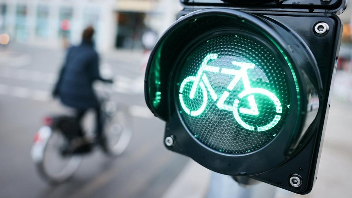 Fahrradfahrer fährt über eine grüne Fahrradfahrer-Ampel (Symbolbild).