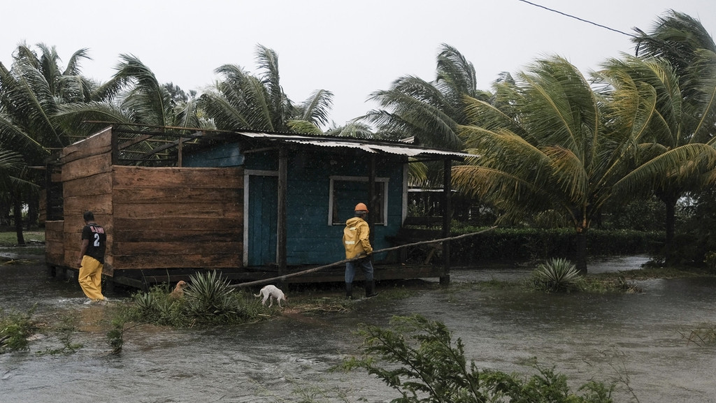 Zwei Männer gehen um ein von Flutwasser umgebenes Haus herum. Der Hurrikan Eta war Anfang November einer der vielen Wirbelstürme des Jahres 2020.
