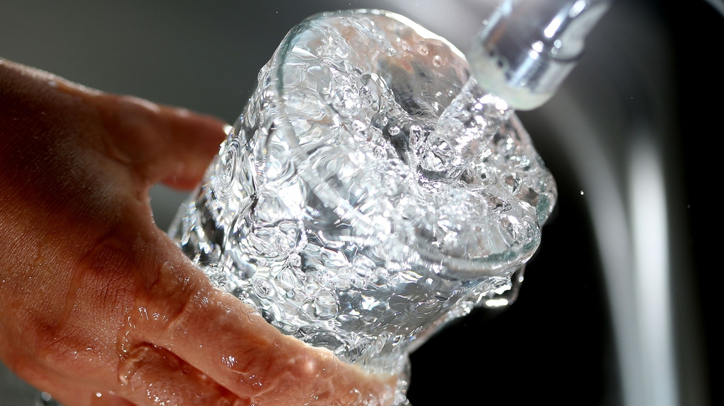 Trinkwasser läuft aus dem Wasserhahn in ein Glas.