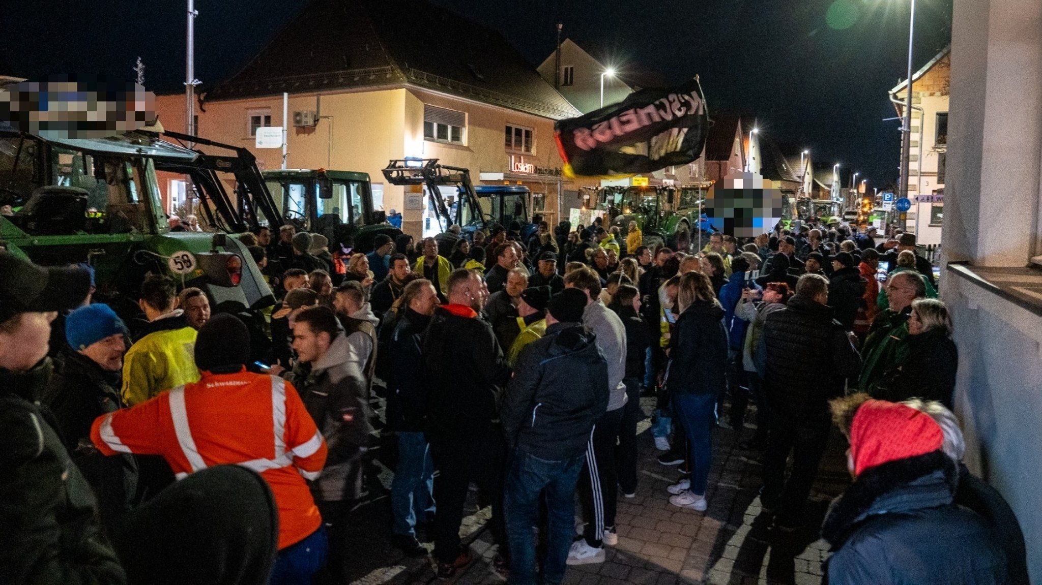 Protestierende Menschen sind zu sehen. Neben ihnen stehen Traktoren. 