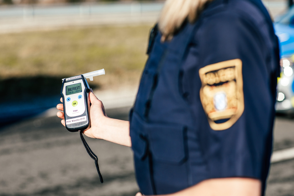 Eine Polizistin hält während einer Fahrzeug- und Personenkontrolle ein Alkoholmessgerät in der Hand (Symbolbild).