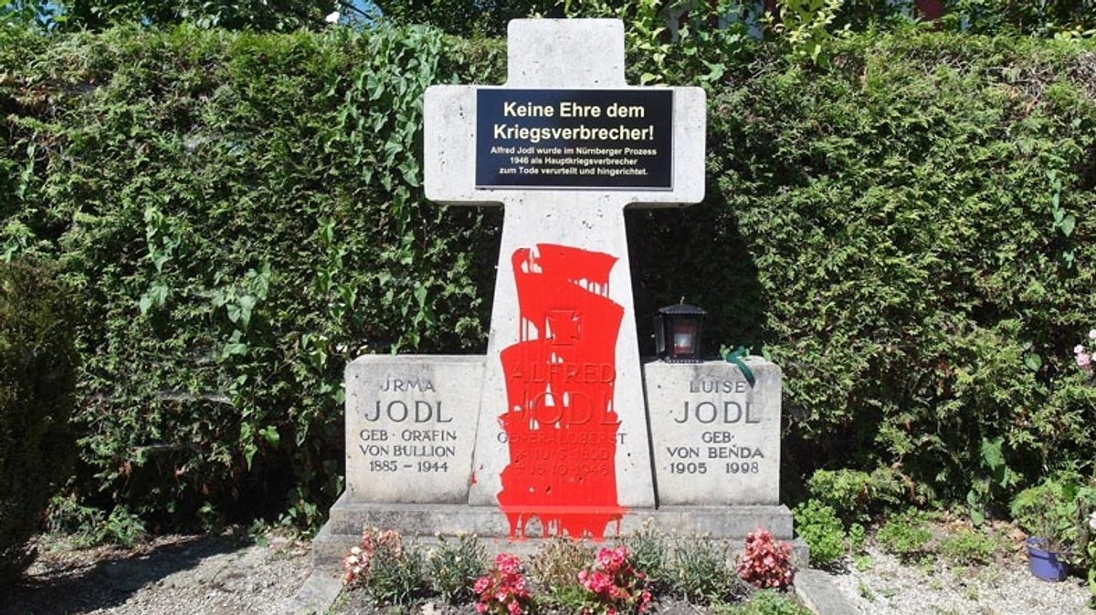 Die Familiengrabstätte der Familie Jodl nach einer Kunstaktion von Wolfram Kastner: Der Kenotaph in der Mitte ist mit roter Farbe übergossen, darüber ein Schild mit der Aufschrift: "Keine Ehre dem Kriegsverbrecher!"