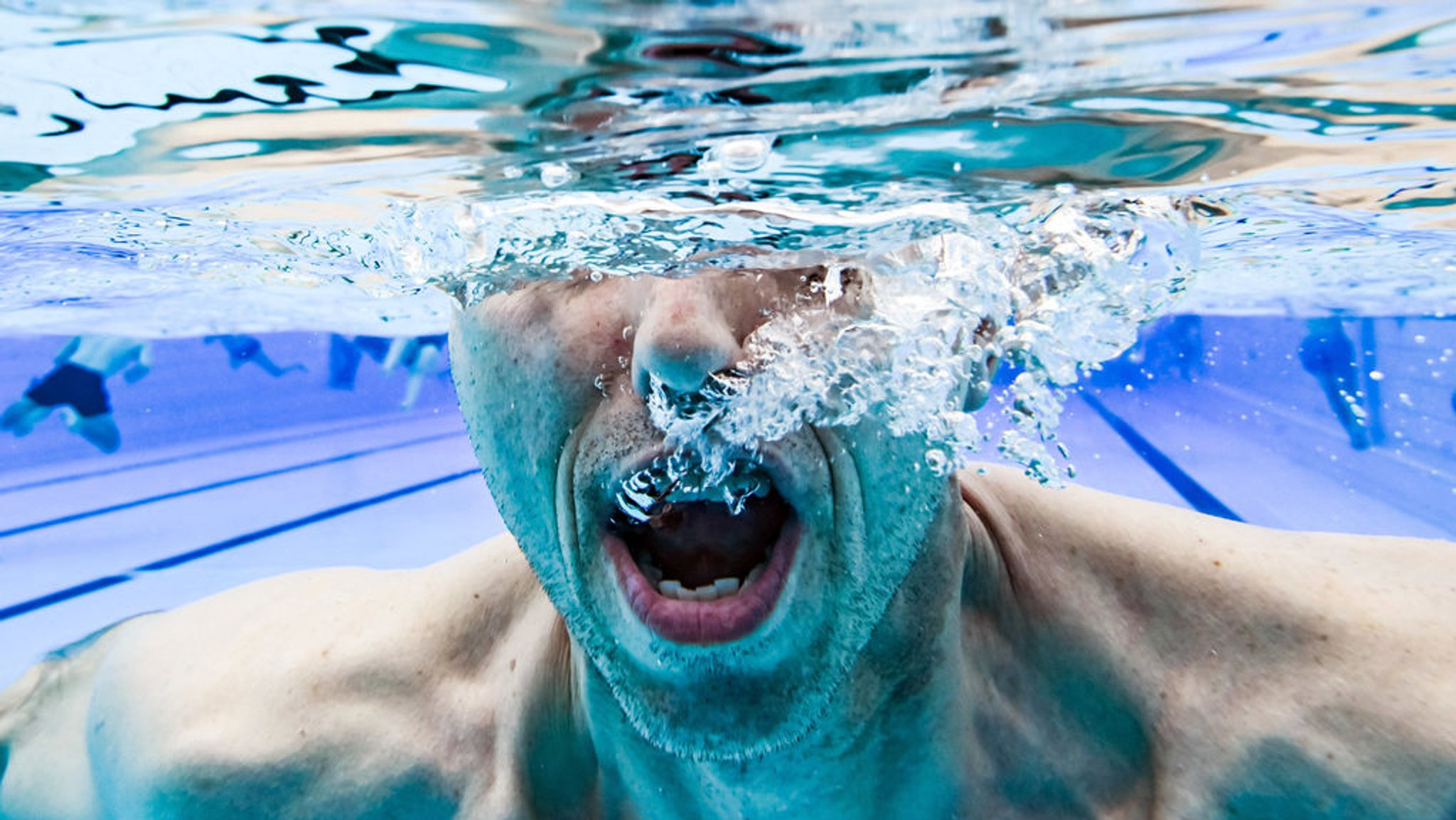 Ein Besucher eines Freibades schwimmt zur Eröffnung durch das Wasser des Beckens.