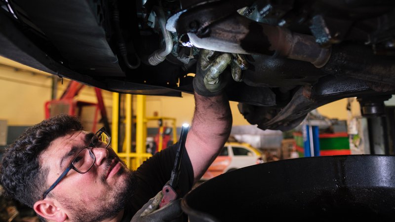 Ein Mann prüft ein Auto von unten | Bild: picture alliance / Westend61 | Angel Santana Garcia Ein Mann prüft ein Auto von unten