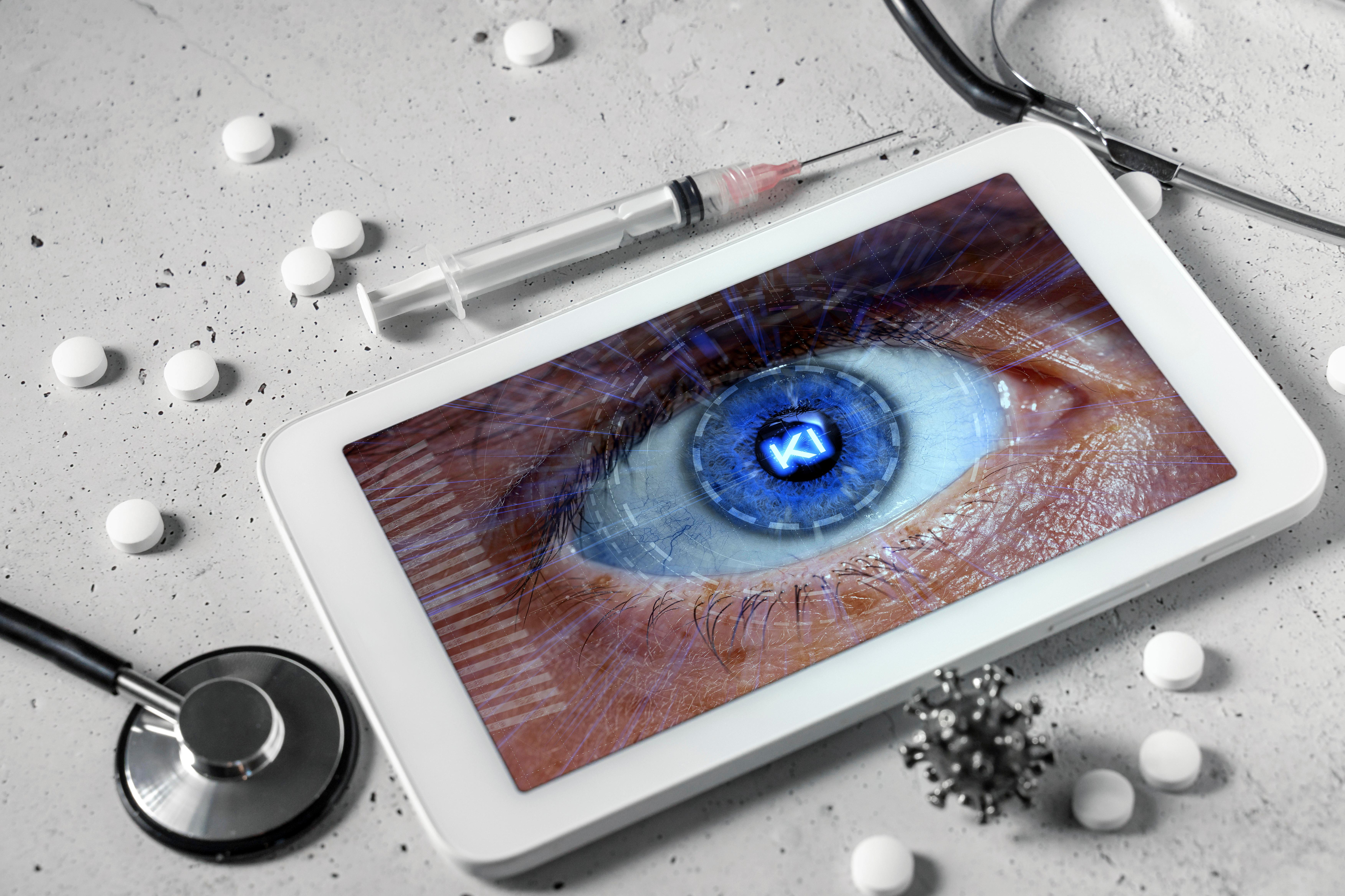 Computer Tablet mit Spritze, Stethoskop und Medizin. Künstliche Intelligenz im medizinischen Bereich Konzept. Tablet mit menschlichem Auge mit aufschrift KI auf dem Bildschirm FOTOMONTAGE 